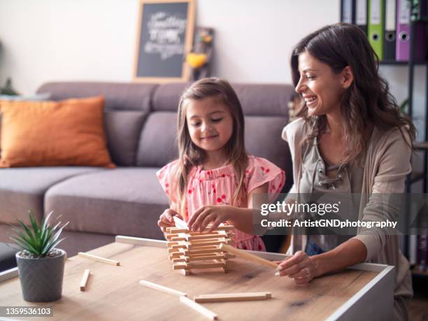 mother and daughter playing jenga at home - block removal game stock pictures, royalty-free photos & images