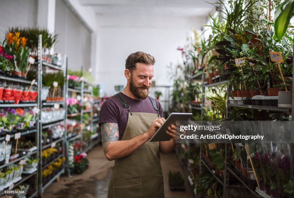 Männlicher Arbeiter im Blumenladen mit digitalem Tablet