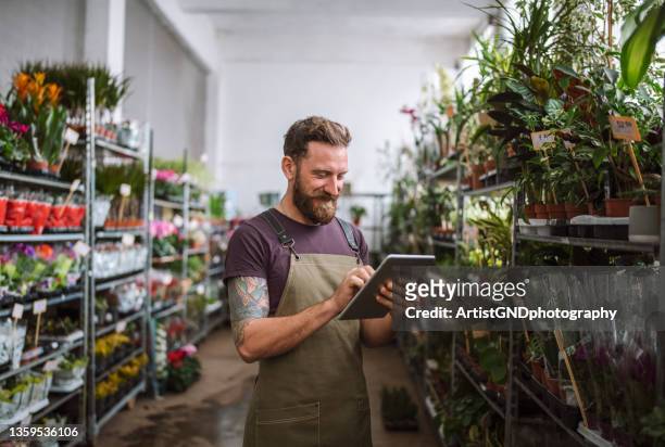 trabalhador masculino em floricultura loja usando tablet digital - local de venda a varejo - fotografias e filmes do acervo