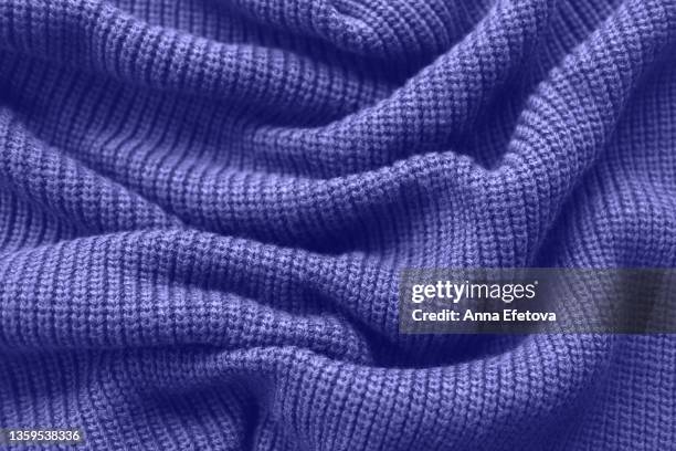 texture of a knitted violet sweater folded in a swirling pattern. flat lay style, close-up. demonstrating very peri - color of 2022 year. - maglione foto e immagini stock