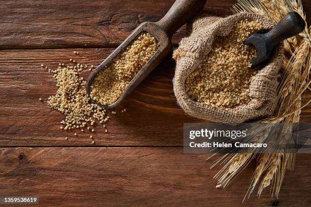 uncooked wheat grain in burlap sack on rustic wooden table - cereales stock pictures, royalty-free photos & images