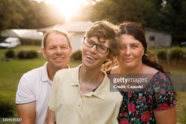 glückliche familie, die beim sonnenuntergang in die kamera schaut - developmental disability stock-fotos und bilder
