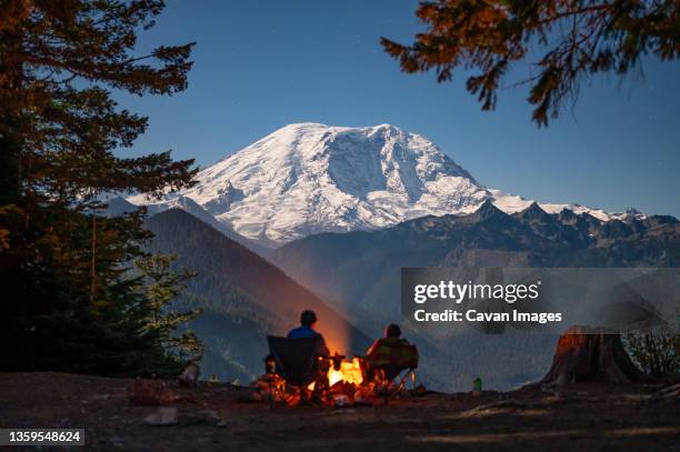 silhouetted campers around the fire with mount rainier behind - seattle stock pictures, royalty-free photos & images