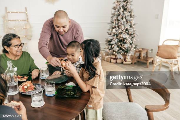 multi-ethnic family having pizza for lunch - filipino family eating stock pictures, royalty-free photos & images