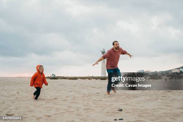 father and son running in the sand at beach in canary islands - family sports centre laughing stock pictures, royalty-free photos & images