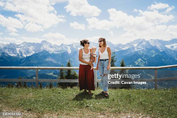 two moms and baby smiling in the mountains in summer - photos of lesbians kissing stock pictures, royalty-free photos & images