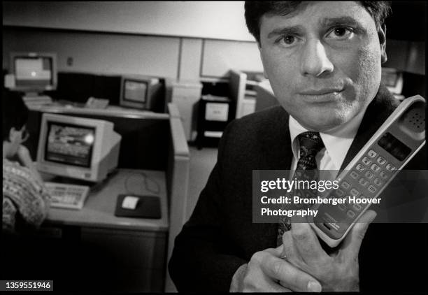 Portrait of American businessman US West Spectrum Enterprises President & CEO John E DeFeo as he poses with a portable telephone, Bellevue,...