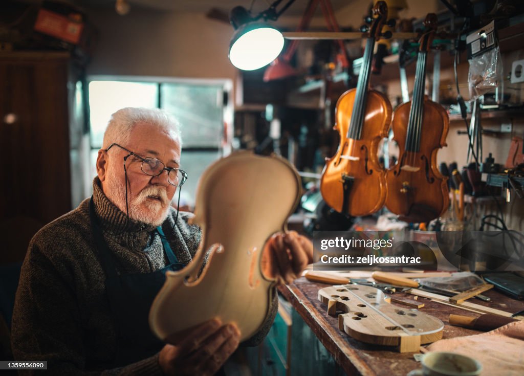Senior craftsman making the violin