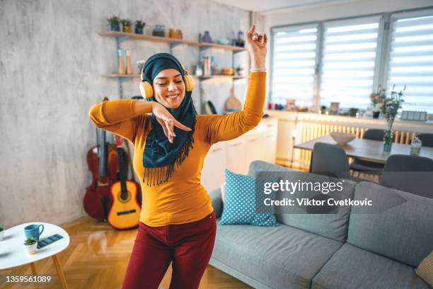 muslim woman listening to music in her apartment - arabic woman listening music stock pictures, royalty-free photos & images