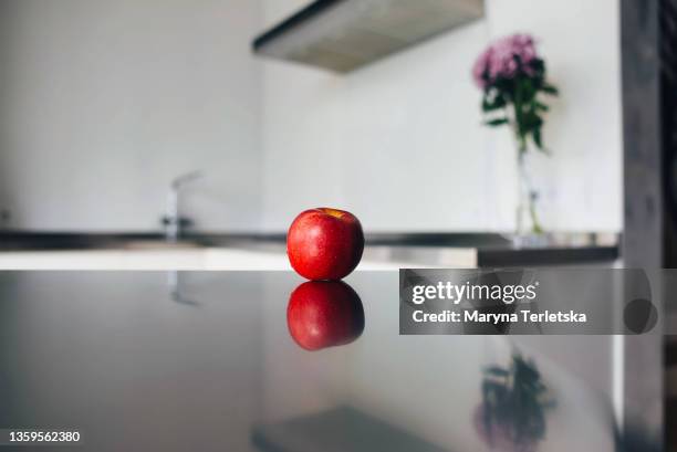 the apple lies on the table against the background of a modern kitchen. - steel furniture stock pictures, royalty-free photos & images