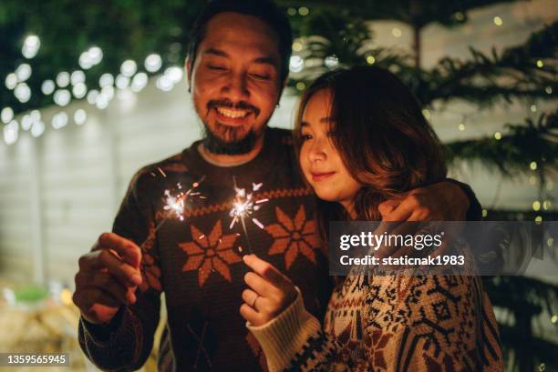 asian friends with sparklers enjoying outdoor party - couple celebrating imagens e fotografias de stock