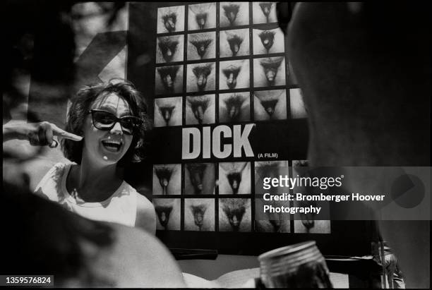 View of people beside a poster for the documentary 'Dick ' , which features a collage of Polaroid photos of penises, San Francisco, California, 1988.