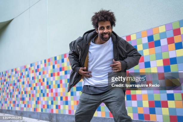 black ethnic man with urban dancer afro hair, performing a modern dance on a colorful background, looking and smiling at the camera - rap battle stock pictures, royalty-free photos & images