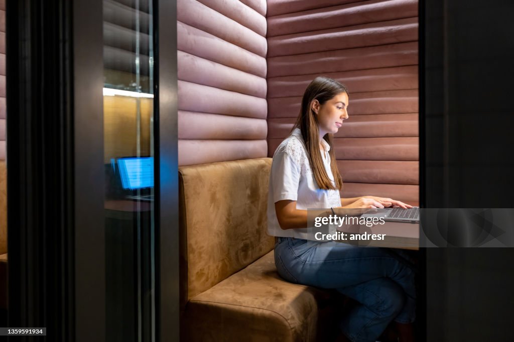Business woman working in an isolated booth at the office