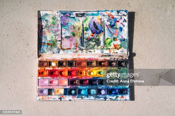 artist's multicolored watercolor palette on textured gray backgr - paint tray fotografías e imágenes de stock