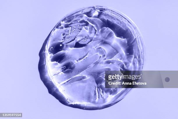 petri dish with transparent cosmetic gel for skin care procedures placed on pastel violet background. photography in flat lay style. polyglutamic acid. demonstrating very peri - color of 2022 year - petri dish stock-fotos und bilder