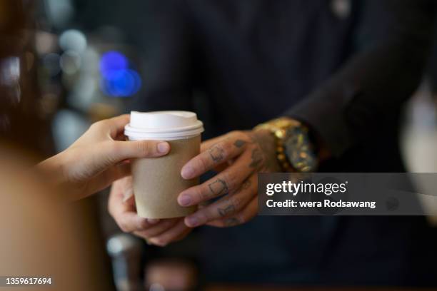 barista serving coffee in takeaway paper disposable cups to client in coffee shop - breakfast to go stock-fotos und bilder