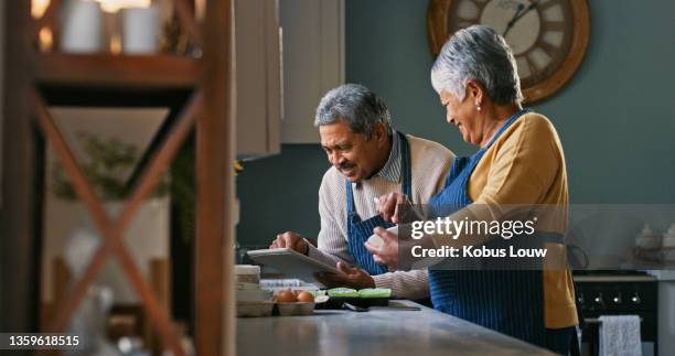 shot of a happy senior couple baking at home - tablet couple stock pictures, royalty-free photos & images