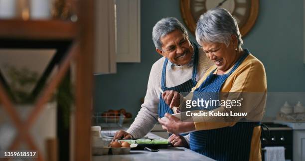 aufnahme eines glücklichen seniorenpaares beim backen zu hause - hispanic couple stock-fotos und bilder