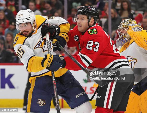 Philipp Kurashev of the Chicago Blackhawks and Alexandre Carrier of the Nashville Predators battle for position in front of Juuse Saros at the United...