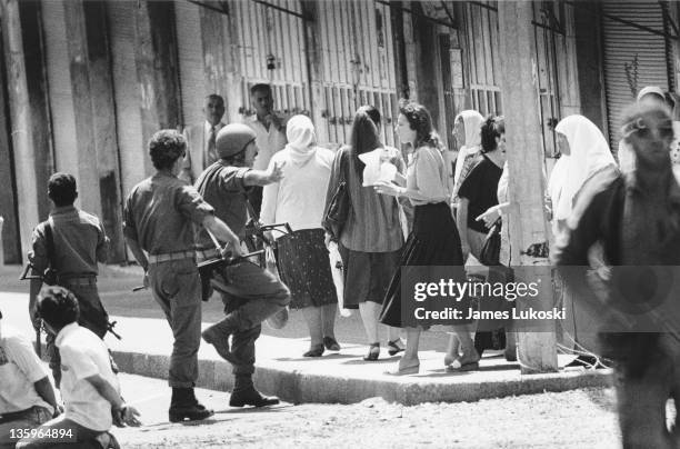 Israeli soldiers are confronted by a group of women in Ramallah, West Bank during the Israeli-Palestinian conflict, circa 1990. On the left are two...