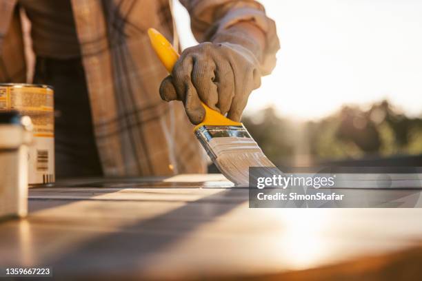 close-up woman with yellow brush,painting old wooden table with sun in background - wood stain stock pictures, royalty-free photos & images