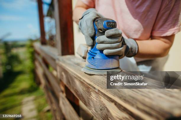 close-up woman using a blue sanding machine on her terrace fence - sander stock pictures, royalty-free photos & images