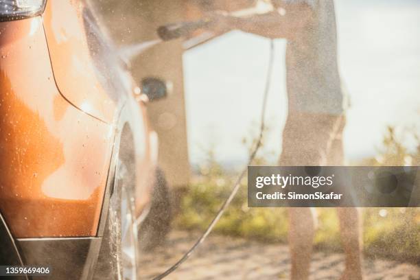 water is distributed in the air through high pressure cleaner used on a car - car splashing water on people stock pictures, royalty-free photos & images