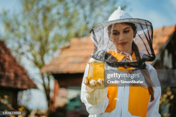 junge imkerin mit einem glas frisch produziertem bienenhonig - beekeeper stock-fotos und bilder