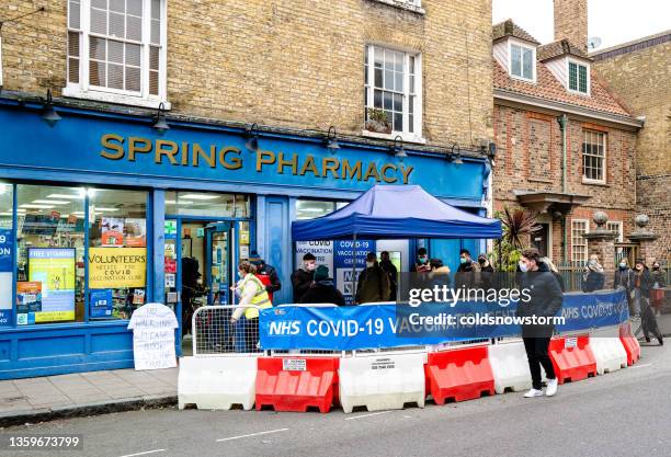 people queuing for covid-19 vaccination outside pharmacy - coronavirus england stock pictures, royalty-free photos & images