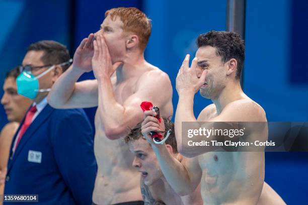 James Guy of Great Britain is overcome with emotion as team mates, Tom Dean and Matthew Richards watch Duncan Scott swimming the last leg during...