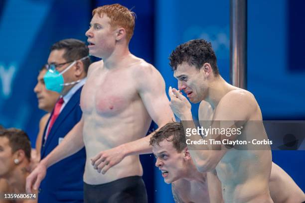 James Guy of Great Britain is overcome with emotion as team mates, Tom Dean and Matthew Richards watch Duncan Scott swimming the last leg during...