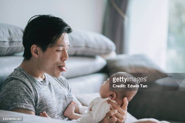 asian chinese young father bonding time playing with his baby boy son at living room during weekend - parental leave stockfoto's en -beelden