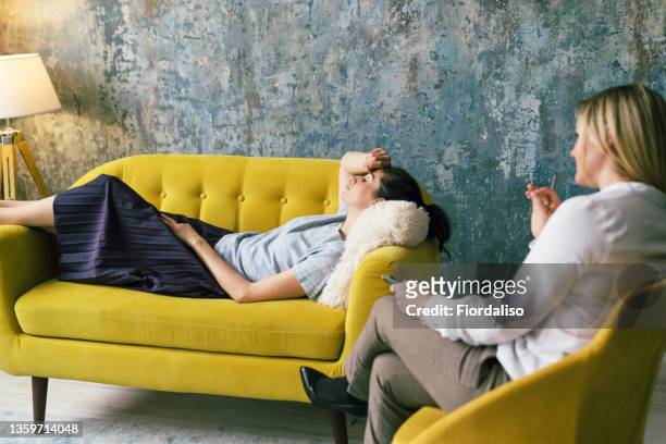 positive blonde middle-aged woman psychologist talking to girl patient - psychiatrists couch fotografías e imágenes de stock