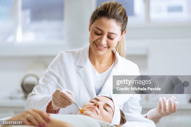 dermatologista feminina realizando procedimento em cliente - terapeuta de beleza - fotografias e filmes do acervo