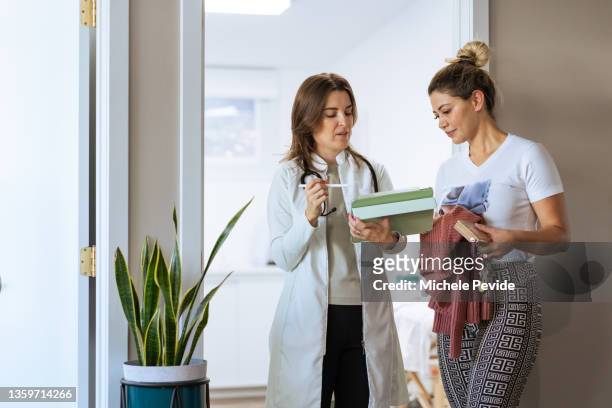 female doctor  holding an ipad and talking with a client - showus doctor stock pictures, royalty-free photos & images