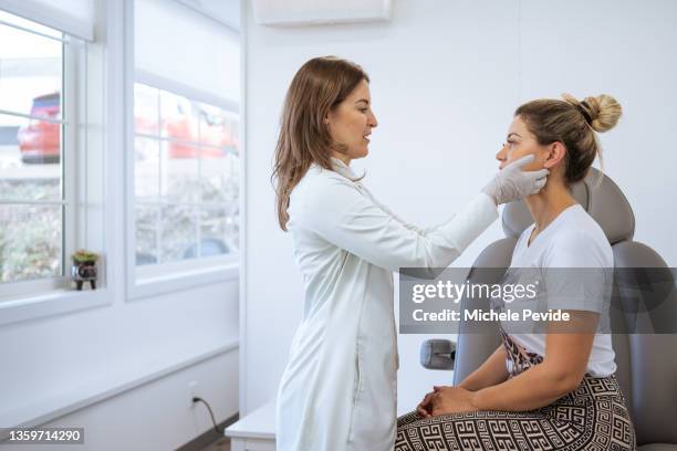 female dermatologist performing a procedure on a client - dermatologie stockfoto's en -beelden