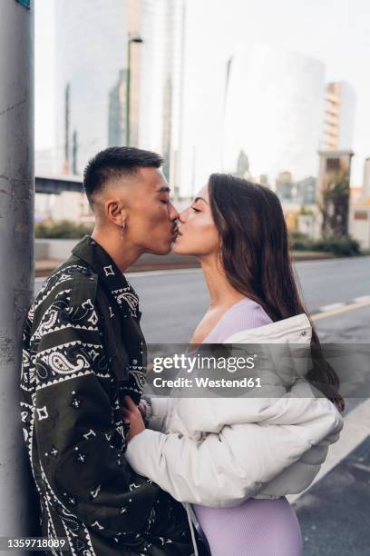 romantic woman kissing boyfriend leaning on pole in city - kyssa på munnen bildbanksfoton och bilder