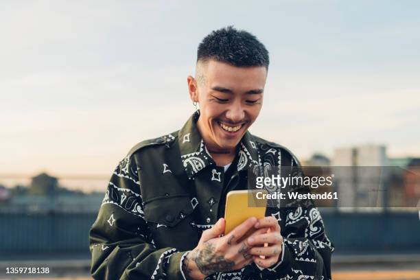 happy hipster man using smart phone at street - milleniumgeneratie stockfoto's en -beelden