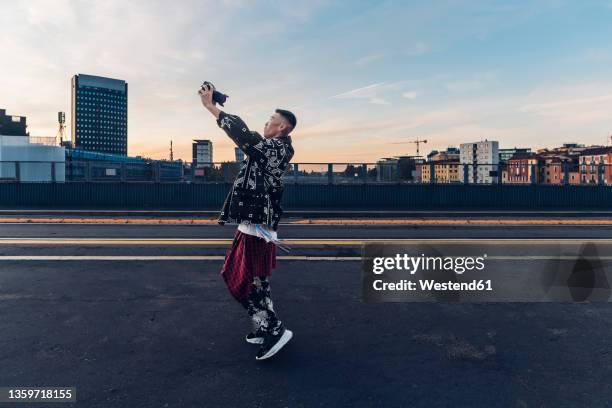 hipster man vlogging through digital camera on road - digital single lens reflex camera stock pictures, royalty-free photos & images