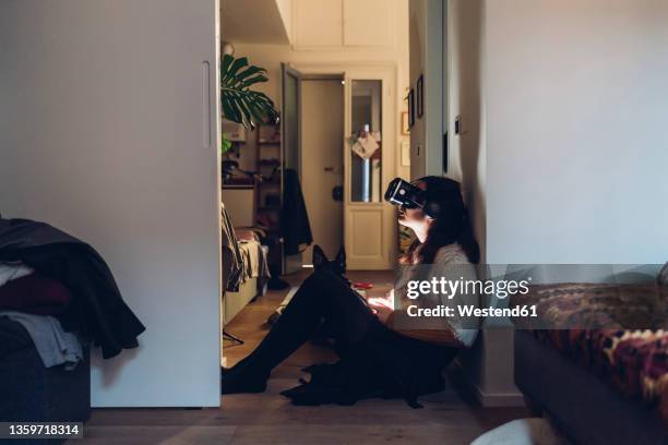woman with virtual reality headset sitting by wall at home - augmented reality animal stock-fotos und bilder