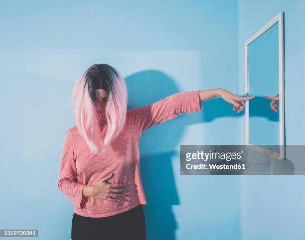 woman pointing at mirror on wall - two tone stock-fotos und bilder
