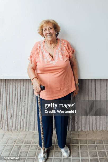 senior woman standing with walking cane on footpath - female cane ストックフォトと画像