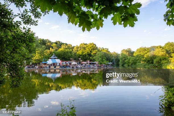 germany, bavaria, munich, mollsee lake in westpark with beer garden in background - biergarten münchen stock pictures, royalty-free photos & images