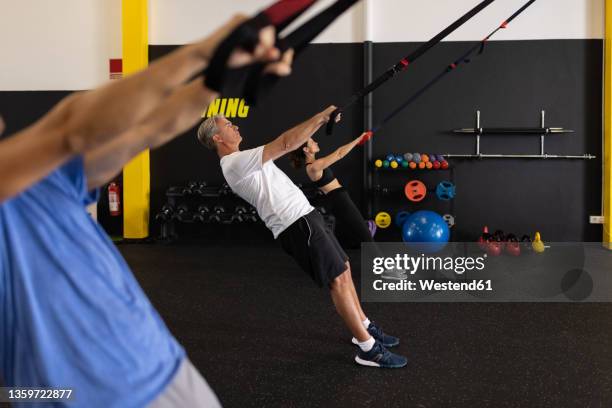 athletes leaning backwards pulling straps in gym - suspension training stock pictures, royalty-free photos & images