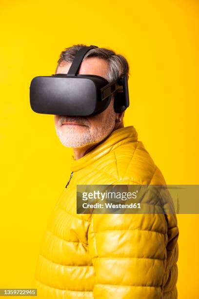 man wearing virtual reality simulator by yellow background - padded jacket 個照片及圖片檔