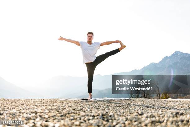 man practicing utthita hasta padangusthasana with mountain view - on one leg stock pictures, royalty-free photos & images