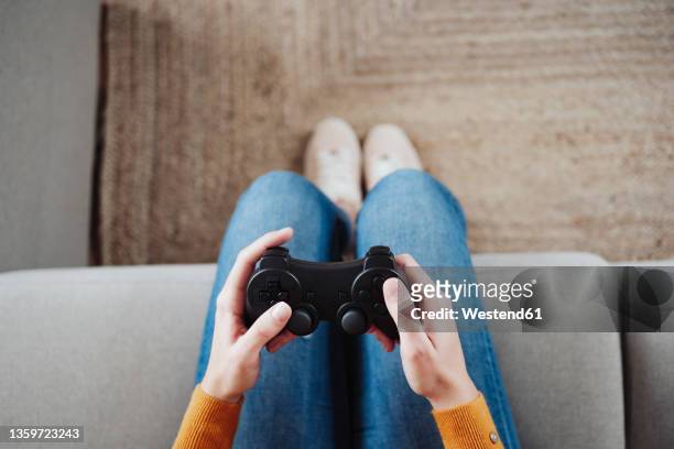 woman playing game with joystick at home - joystick stock-fotos und bilder