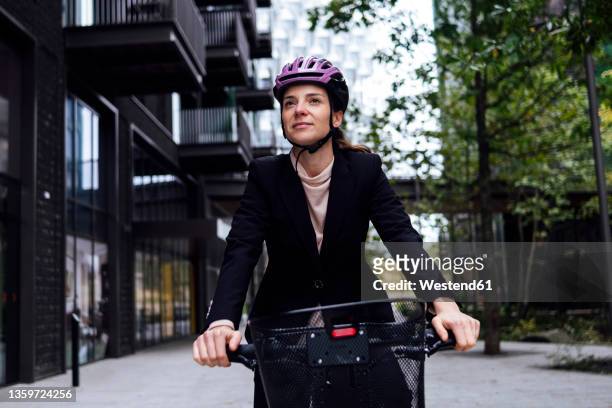 businesswoman riding electric bicycle in city - biking stock pictures, royalty-free photos & images