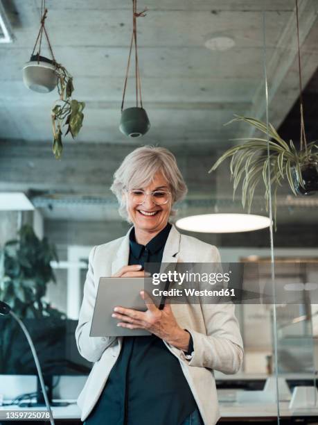 smiling senior businesswoman using tablet pc at office - formelle geschäftskleidung stock-fotos und bilder